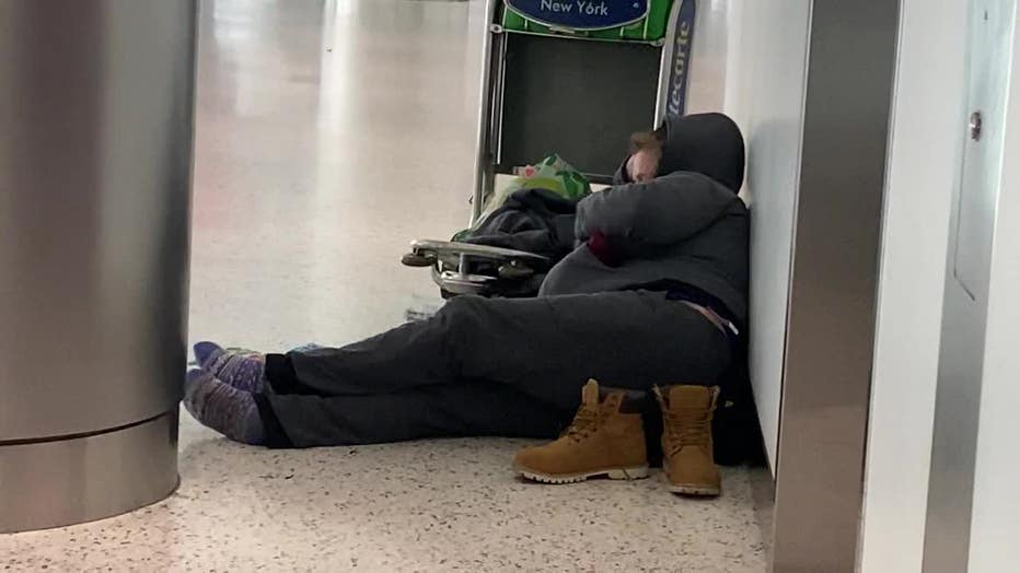 A person sleeps on the floor at JFK Airport.