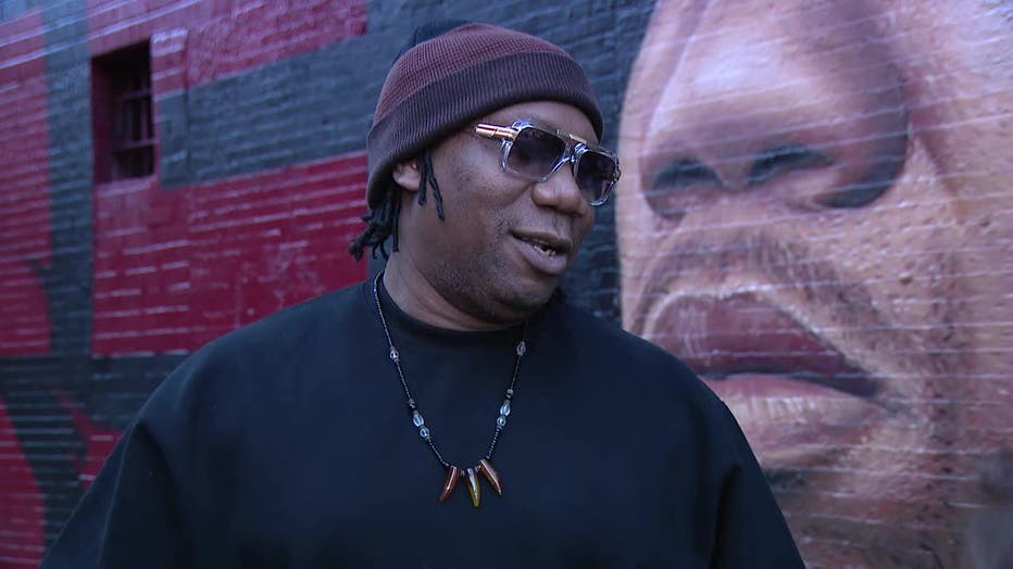 KRS-One stands in front of a mural of himself on the Lower East Side.