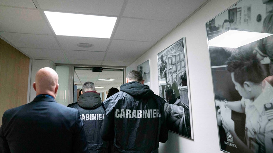 Italian carabinieri walk in a corridor at the Interpol headquarters in Lyon, central France, Thursday, Feb.2, 2023. An Interpol statement said French police, with help from Italian colleagues, arrested Edgardo Greco in Saint-Etienne, central France. He was wanted for two murders in 2006 and accused of attempted murder in another case. Italian authorities said the two people killed in 2006 were brothers who were beaten to death with a metal bar in a fish shop in Calabria. (Interpol via AP)