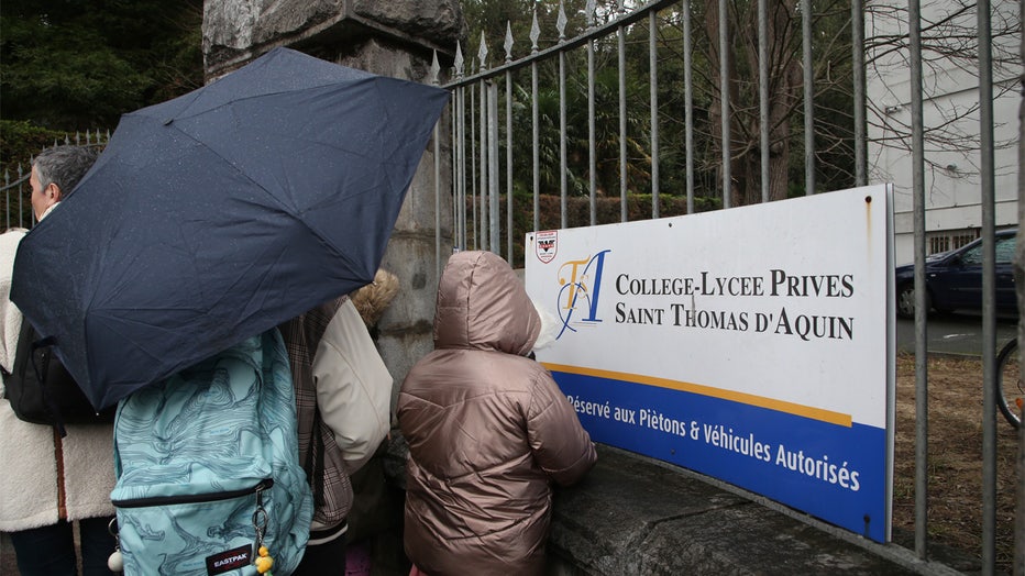 A child looks through the entrance of a private Catholic school after a teacher has been stabbed to death by a high school student, Wednesday, Feb. 22, 2023 in Saint-Jean-de-Luz, southwestern France. The student has been arrested by police, the prosecutor of Bayonne said. (AP Photo/Bob Edme)