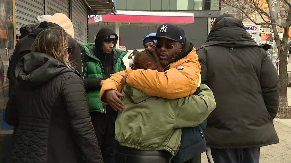 Robert Burrell, the father of the victims, hugs someone outside of the store.