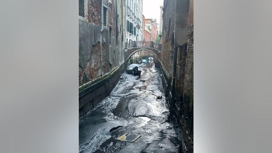 Boats are docked on a dry canal during a low tide in Venice, Italy, Monday, Feb. 20, 2023. (AP Photo/Luigi Costantini)