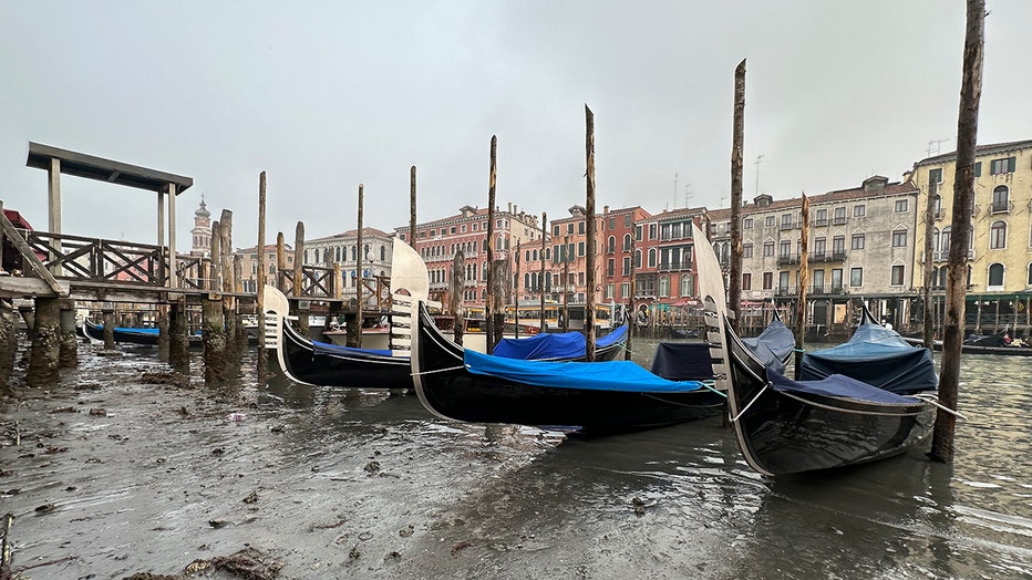 Gondolas are docked along a canal with a low water level during a low tide in Venice, Italy, Saturday, Feb. 18, 2023. (AP Photo/Luigi Costantini)