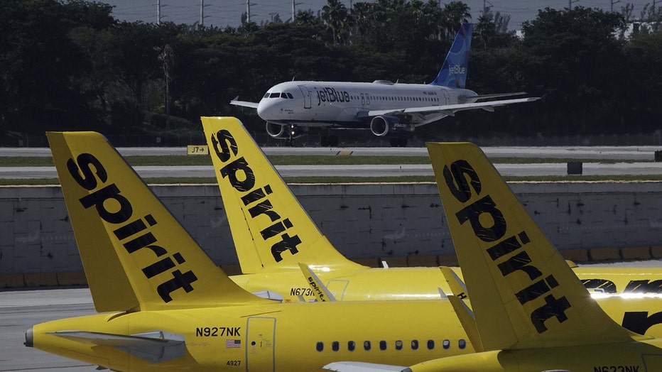 A JetBlue airliner takes off past Spirit Airlines planes at Fort Lauderdale-Hollywood International Airport. JetBlue is waging major campaign to win federal approval for its proposed Spirit buyout, which is opposed by some who claim it will diminish competition. (Joe Cavaretta/Sun Sentinel/Tribune News Service via Getty Images)