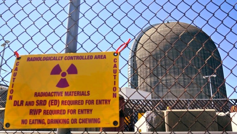 FILE - A sign warning of radioactive materials is seen on a fence around a nuclear reactor containment building, April 26, 2021, a few days before it stopped generating electricity at Indian Point Energy Center in Buchanan, N.Y. The Indian Point nuclear plant along the Hudson River is at the center of a controversy two years after it was shut down. The latest flashpoint revolves around plans to release 1.3 million gallons of water with trace amounts of radioactive tritium into the river as part of the plant’s decommissioning. (AP Photo/Seth Wenig, File)
