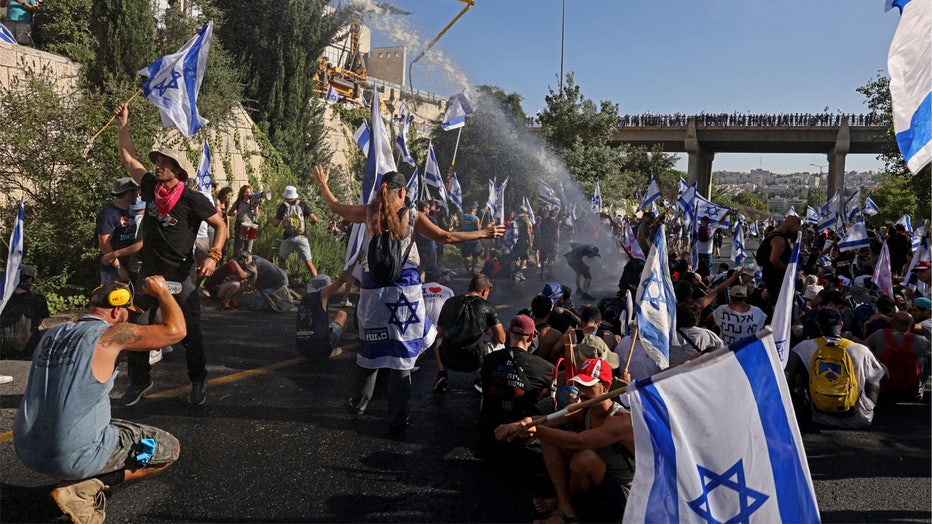 Israeli security forces use a water cannon to disperse demonstrators blocking the entrance of the Knesset, Israel's parliament, in Jerusalem on July 24, 2023, amid a months-long wave of protests against the government's planned judicial overhaul. Israel's hard-right government pushed through parliament a key clause of its controversial judicial reform package despite months of mass protests and concerns voiced by foreign allies. (Photo by HAZEM BADER / AFP) (Photo by HAZEM BADER/AFP via Getty Images)