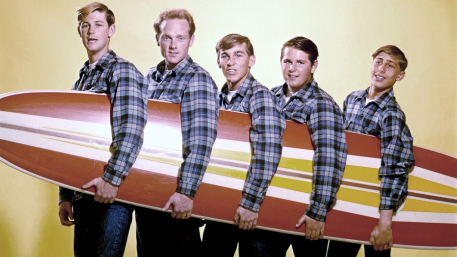 LOS ANGELES - AUGUST 1962: Rock and roll band "The Beach Boys" pose for a portrait with a surfboard in August 1962 in Los Angeles, California. (L-R) Brian Wilson, Mike Love, Dennis Wilson, Carl Wilson, David Marks. This image was used on the cover of 'Surfin' USA'. (Photo by Michael Ochs Archives/Getty Images)