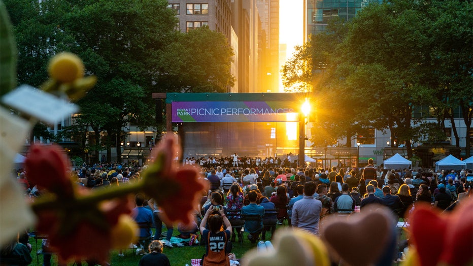 NEW YORK, NEW YORK - JUNE 12: The sun sets behind The New York Philharmonics concert at the Picnic Performances in Bryant Park on June 12, 2021 in New York City. On June 9th, the Picnic Performances in Bryant Park sponsored by Bank of America returned for the summer after being cancelled in 2020 due to the coronavirus pandemic. The performances continue until mid September 2021. New York Governor Andrew Cuomo announced pandemic restrictions to be lifted on May 19. (Photo by Alexi Rosenfeld/Getty Images)
