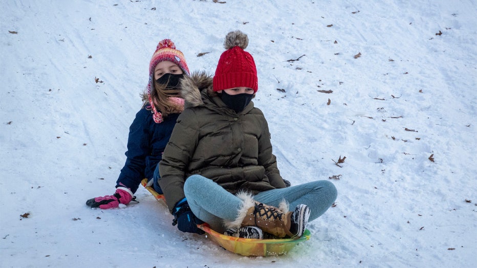 Two young girls sledding on snow at Riverside Park in Manhattan, NYC. (Photo by: Peter Titmuss/Education Images/Universal Images Group via Getty Images)
