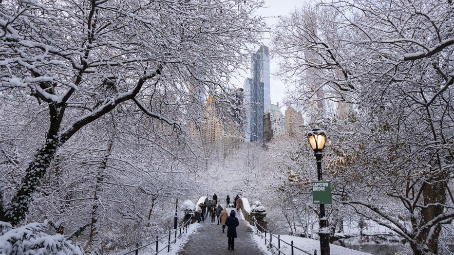 NEW YORK, NEW YORK - DECEMBER 21: People walk over the Gapstow Bridge as snow falls in Central Park on December 21, 2024 in New York City. (Photo by Craig T Fruchtman/Getty Images)