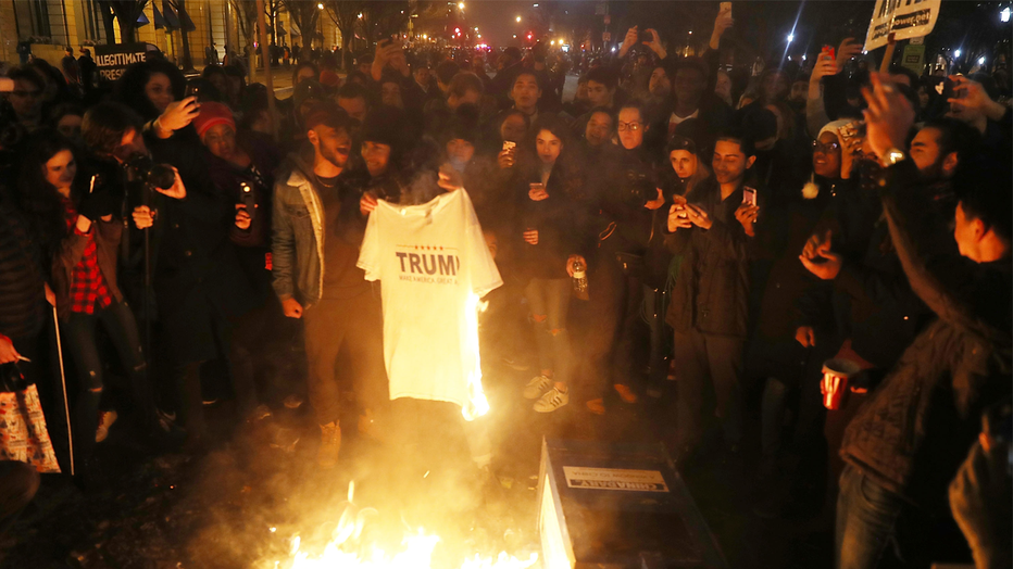 WASHINGTON, DC - JANUARY 20: Protesters set a Trump tee-shirt on fire in the street as they make themselves heard following the inauguration of President Donald Trump on January 20, 2017 in Washington, DC. Earlier today Donald Trump was inaugurated as the 45th President of the United States. (Photo by Joe Raedle/Getty Images)