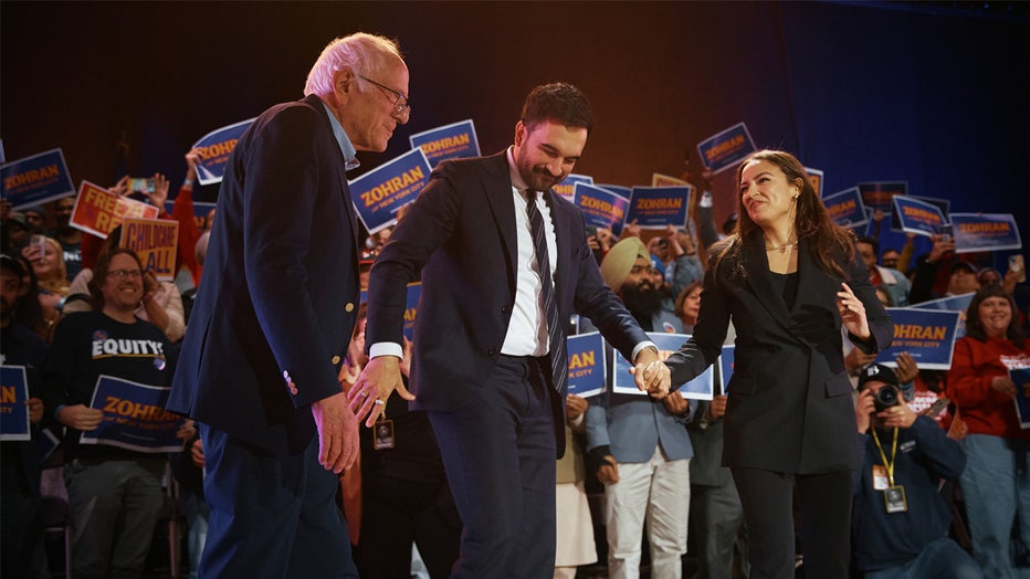 NEW YORK, NEW YORK - OCTOBER 26: New York Mayoral Candidate Zohran Mamdani (C) salutes with Sen. Bernie Sanders (I-VT), left, and U.S. Rep. Alexandria Ocasio-Cortez (D-NY), right, during an election rally at Forest Hills Stadium on October 26, 2025 in the Queens borough of New York City. The mayoral election will take place on November 4, 2025. (Photo by Andres Kudacki/Getty Images)