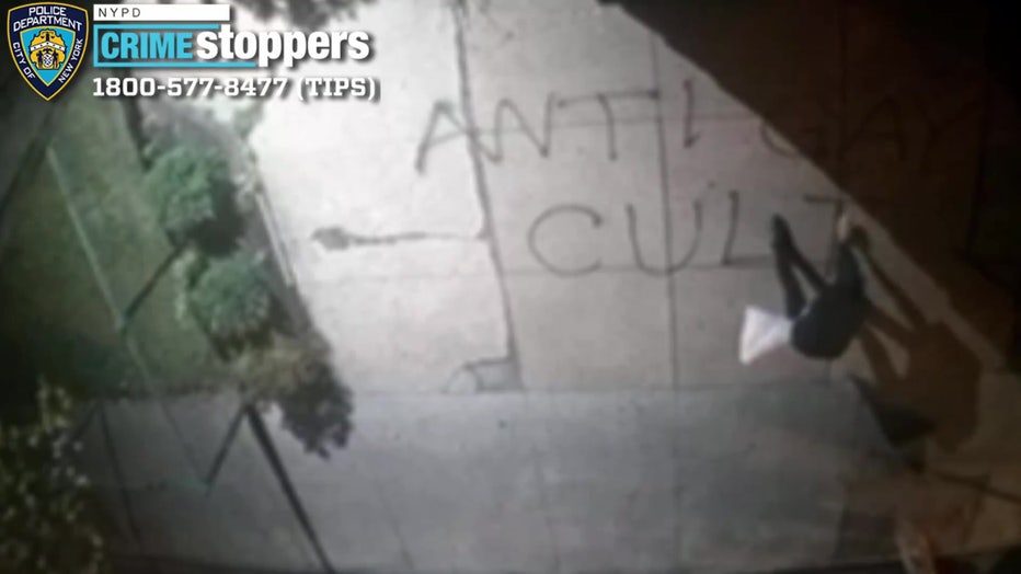 A person spray-painting a sidewalk with the words "anti-gay cult."