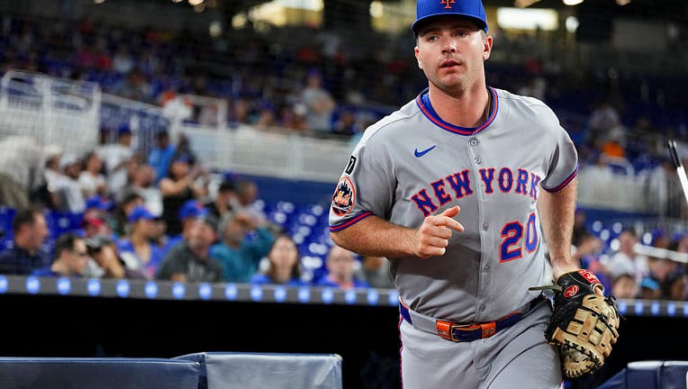 Pete Alonso in a grey New York Mets jersey and blue cap, running out of the dugout at LoanDepot Park toward the camera.
