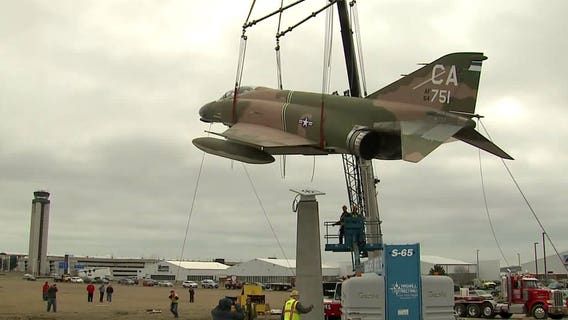 "Emblem of the heroes of America:" Vietnam era fighter hoisted into place at Mitchell Intl. Airport