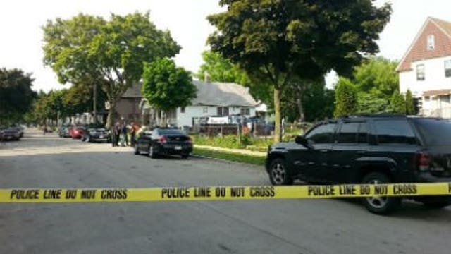 Around 20 people in handcuffs, neighbors watch what looks like a scene from a movie