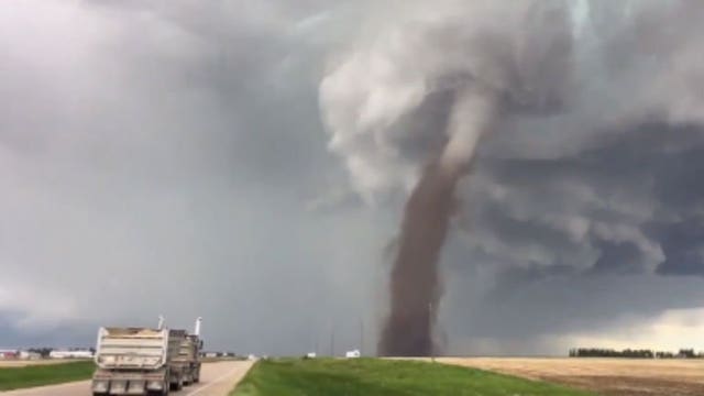 "Keeping an eye on it:" Photo of man mowing as tornado swirls behind him goes viral