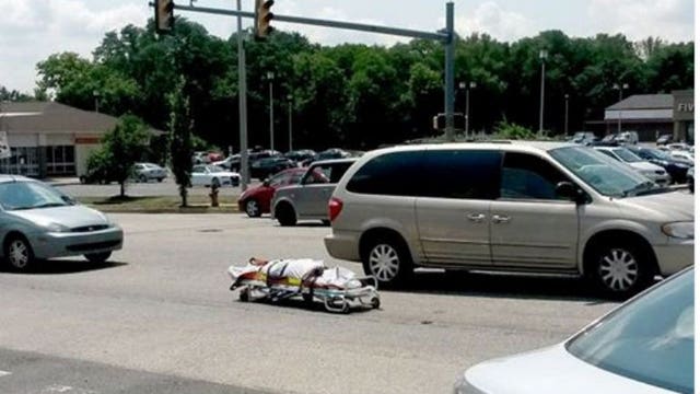 A coroner van loses a passenger... When a corpse on a stretcher flies out of vehicle right on to the street!