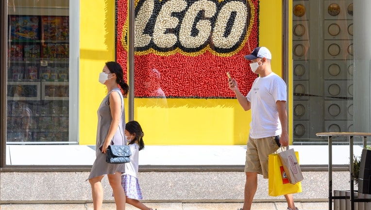 NEW YORK, NEW YORK - SEPTEMBER 07: People wear protective face masks as they leave the Lego store in Rockefeller Center during Phase 4 of re-opening following restrictions imposed to slow the spread of coronavirus on September 7, 2020 in New York City. The fourth phase allows outdoor arts and entertainment, sporting events without fans and media production. (Photo by Noam Galai/Getty Images)