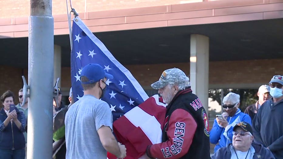 Military veterans replace a flag at Longfellow Middle School that had been taken down amid protests