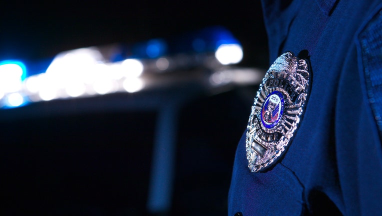 Close-up of an officer's badge with the police lights on the car flashing in the background