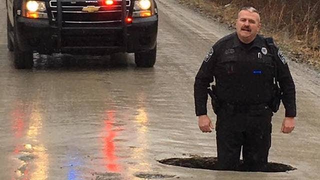 Michigan pothole so large police officer stands knee-deep