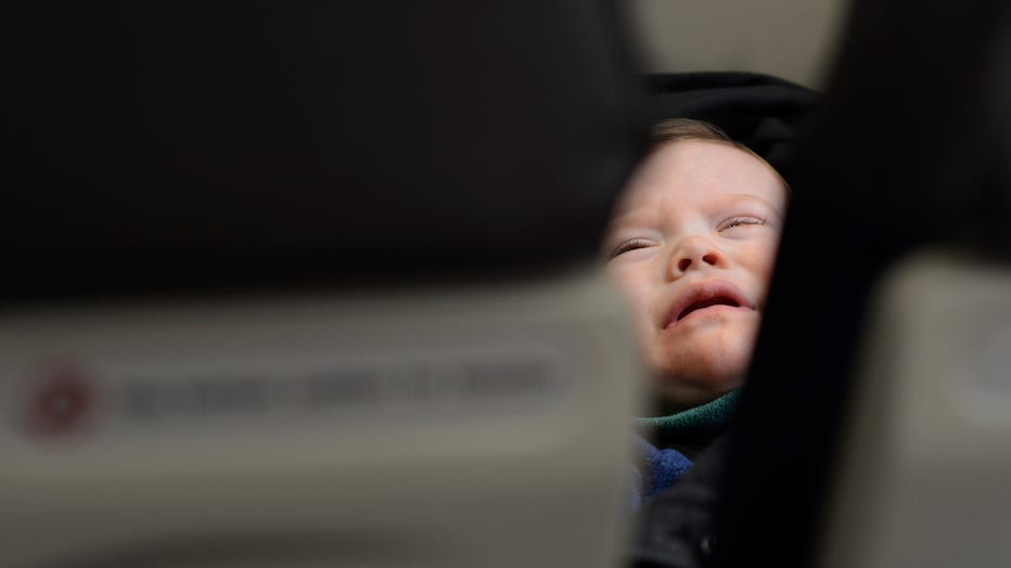 A file image shows a toddler crying in the seat beside his mother as they fly in a passenger jet departing from Dallas/Fort Worth International Airport. (Photo by Robert Alexander/Getty Images)