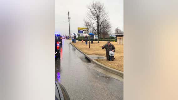 Photo shows stranger kneeling in rain during procession of fallen police officer