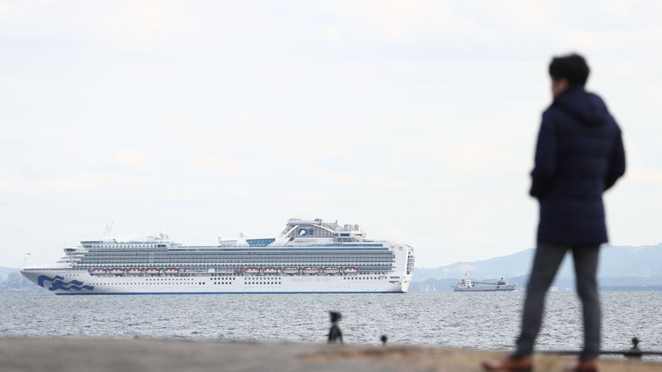 8822e1dd-A member of the media looks out toward the Diamond Princess cruise ship (L) with over 3,000 people as it sits anchored in quarantine off the port of Yokohama on February 4, 2020, a day after it arrived with passengers feeling ill.