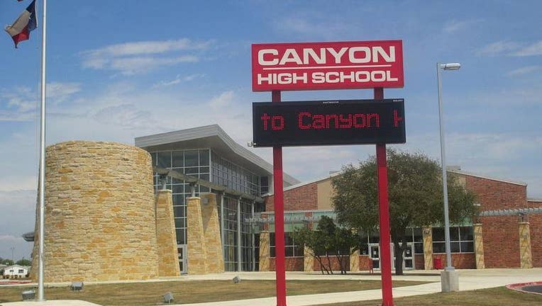 A photo of the exterior of Canyon High School in Comal County, Texas with the large red sign proclaiming the school's name and an LED sign beneath saying "to Canyon High"