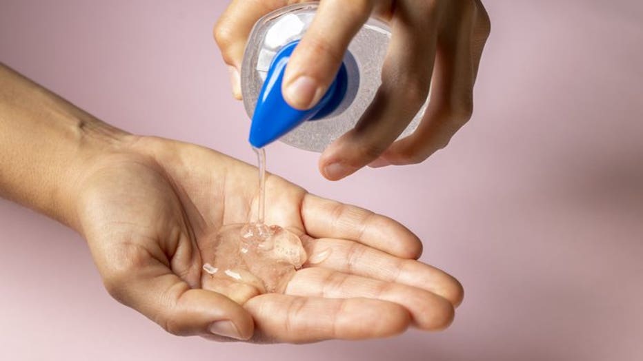 FILE - Woman using alcohol-based hand sanitizer.