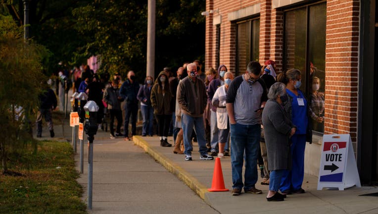 Several voters wearing masks are seen lined up outside