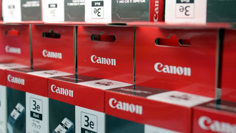 Canon Inc. printer ink cartridges sit on a shelf at an elect
