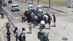 Video shows bystanders lifting car to rescue pinned motorcyclist after crash