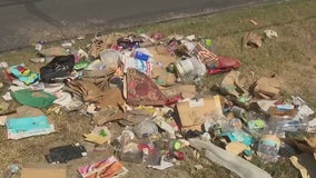 Austin garbage truck dumps trash on side of the road