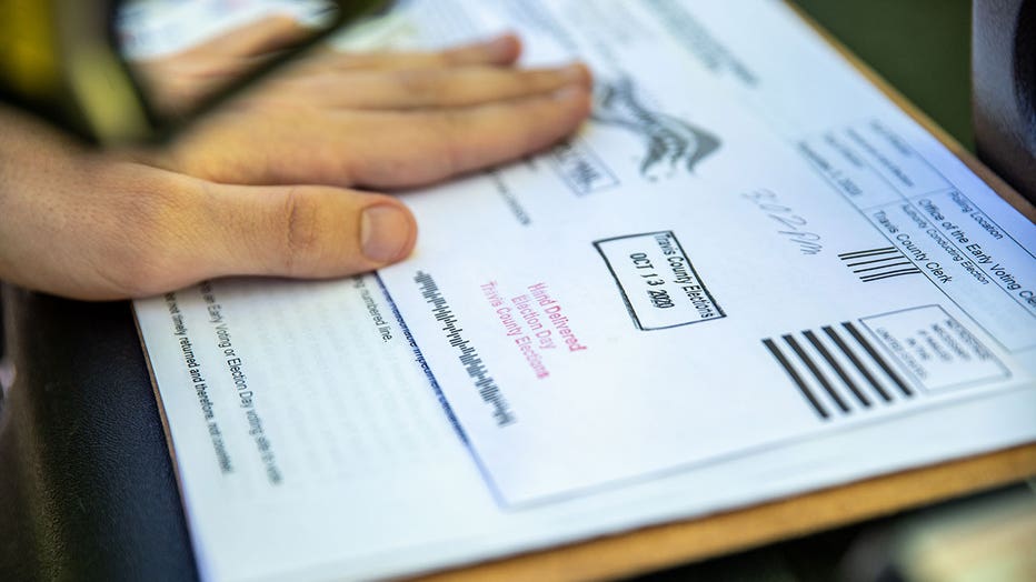 A poll worker stamps a voters ballot before dropping it into a secure box at a ballot drop off location on October 13, 2020 in Austin, Texas.