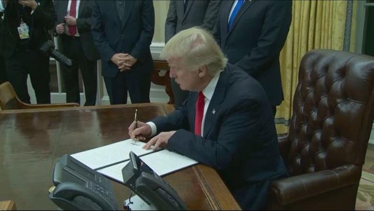 d26b96fb-trump signs executive order_1484962480687.JPG