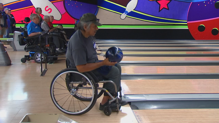 Man in wheelchair tosses bowling ball.