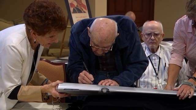 WWII veterans sign names on model B-25 to fly in special ceremony