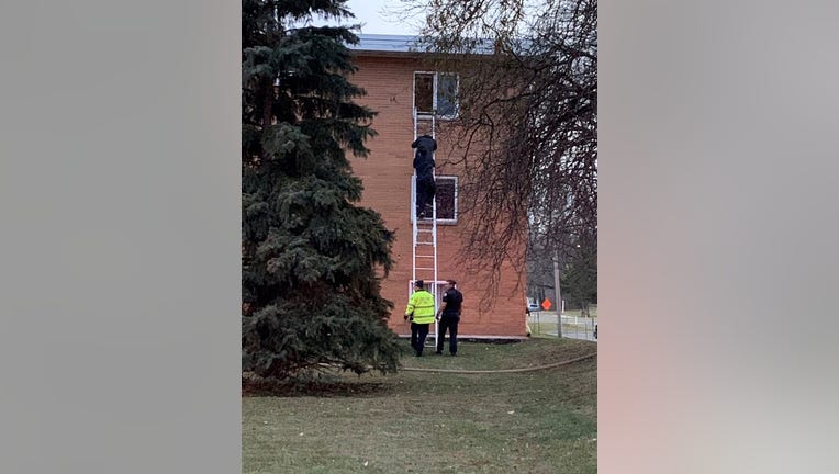 Fire crews help residents down a ladder during a fire. 