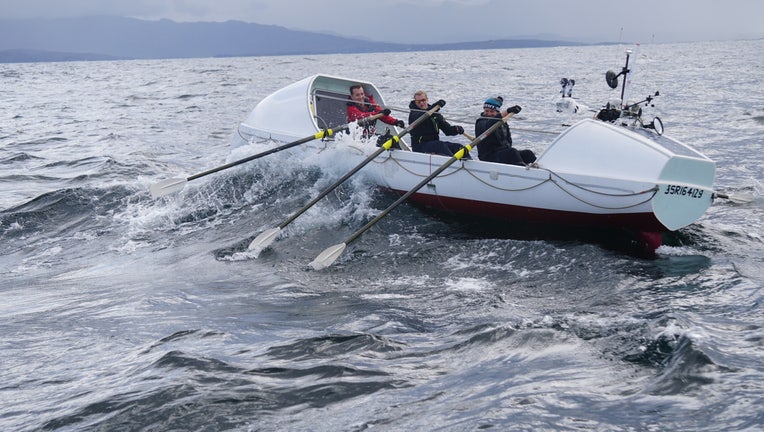 Men row a large row boat