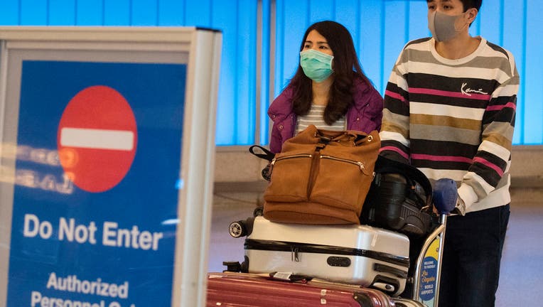 Passengers wear protective masks to protect against the spread of the Coronavirus as they arrive at the Los Angeles International Airport, California, on January 22, 2020. - A new virus that has killed nine people, infected hundreds and has already reached the US could mutate and spread, China warned on January 22, as authorities urged people to steer clear of Wuhan, the city at the heart of the outbreak. 