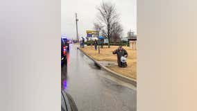 Photo shows stranger kneeling in rain during procession of fallen police officer