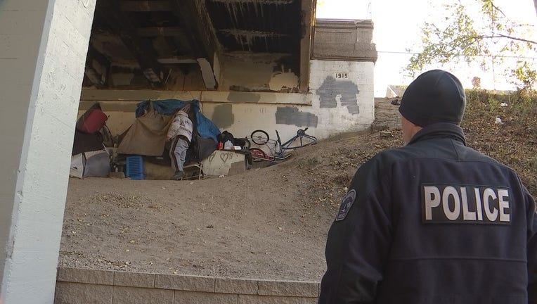 A member of Minneapolis Police Department's new homeless initiative does a routine check-in on a person experiencing homelessness along the Midtown Greenway. 