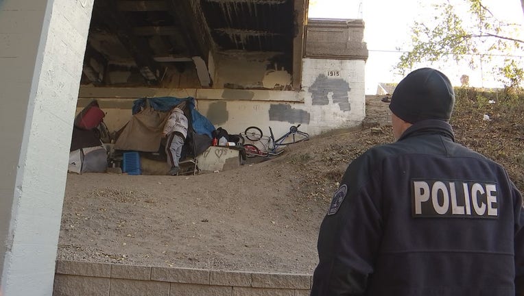 A member of Minneapolis Police Department's new homeless initiative does a routine check-in on a person experiencing homelessness along the Midtown Greenway.