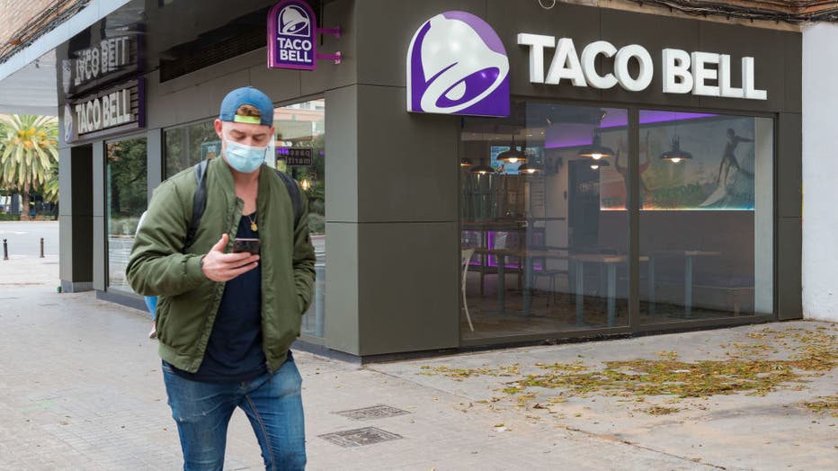 A man wearing a face mask walks past a fast food restaurant
