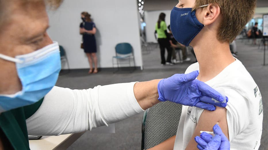 A nurse gives Nicholas Miles, 13, a shot of the vaccine at a