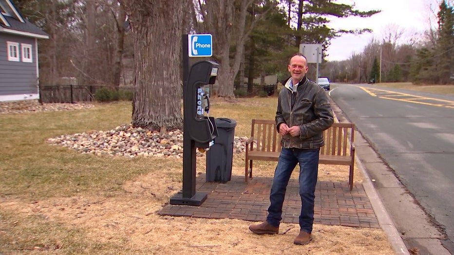 Drian Davis stands next to his payphone