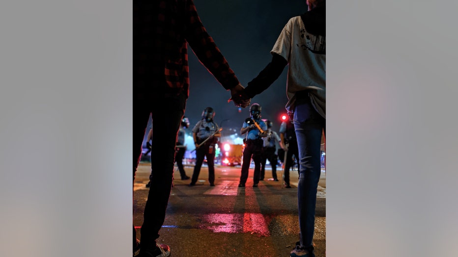 Protesters hold hands as they face a line of police officers during demonstrations following the murder of George Floyd in Minneapolis.