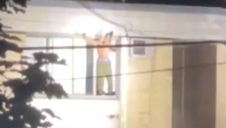 A screengrab of a livestream of the standoff betwen Tekle Sundberg and Minneapolis Police shows Sunderberg standing on the ledge of this third floor apartment window.